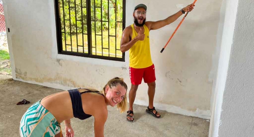 two gap year students paint a wall during a service project with outward bound
